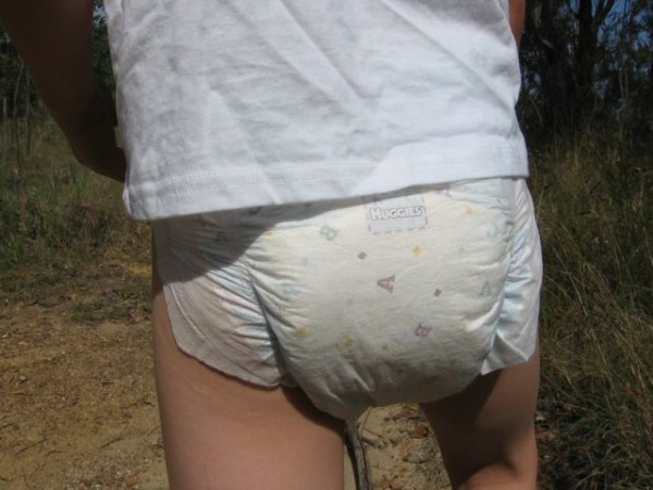 Older kid boy 8 year old boy wearing huggies diapers and shirt outside
