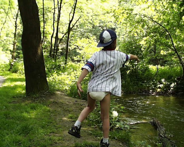 8 year old diaper boy outside playing in diaper and shirt