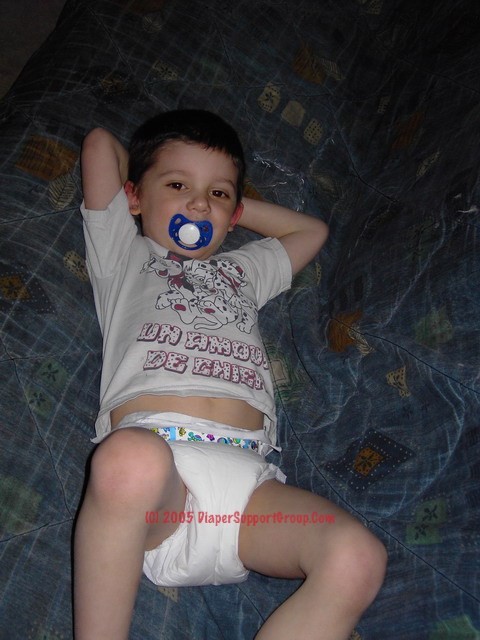5 year old boy wearing plastic backed diapers and sucking on pacifier.