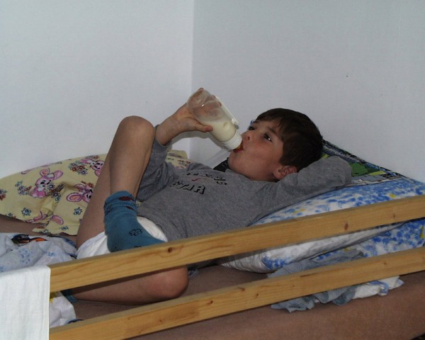 8 year old diaper boy drinking milk from bottle