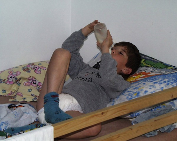 8 year old diaper boy drinking milk from bottle
